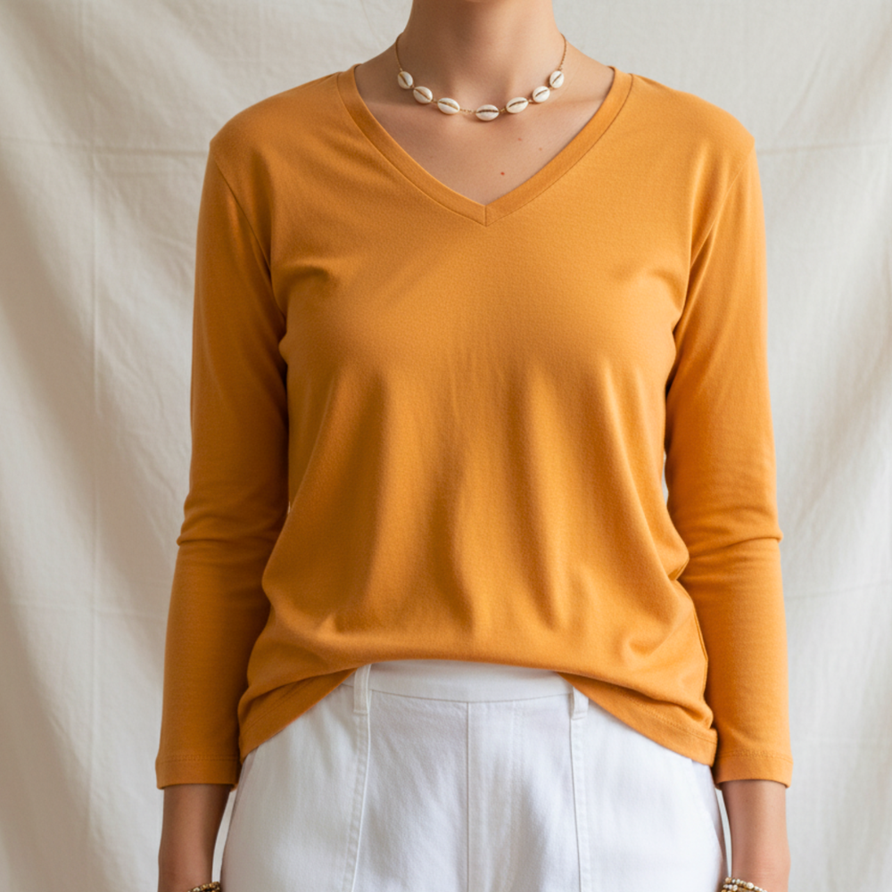 Person wearing a cotton mustard yellow long-sleeve top against a plain background