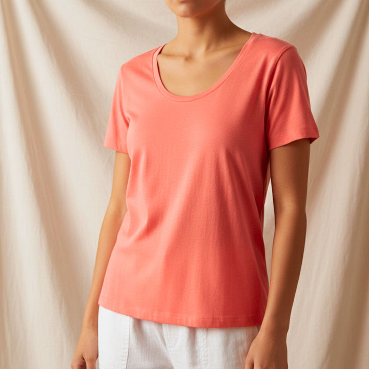 Person wearing a cotton coral t-shirt against a beige background