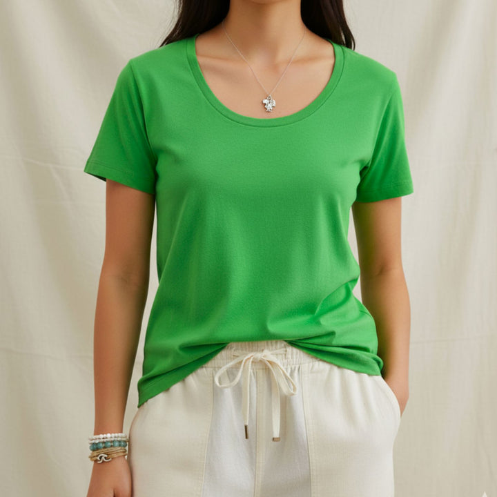 Person wearing an organic cotton green t-shirt and white pants against a plain background