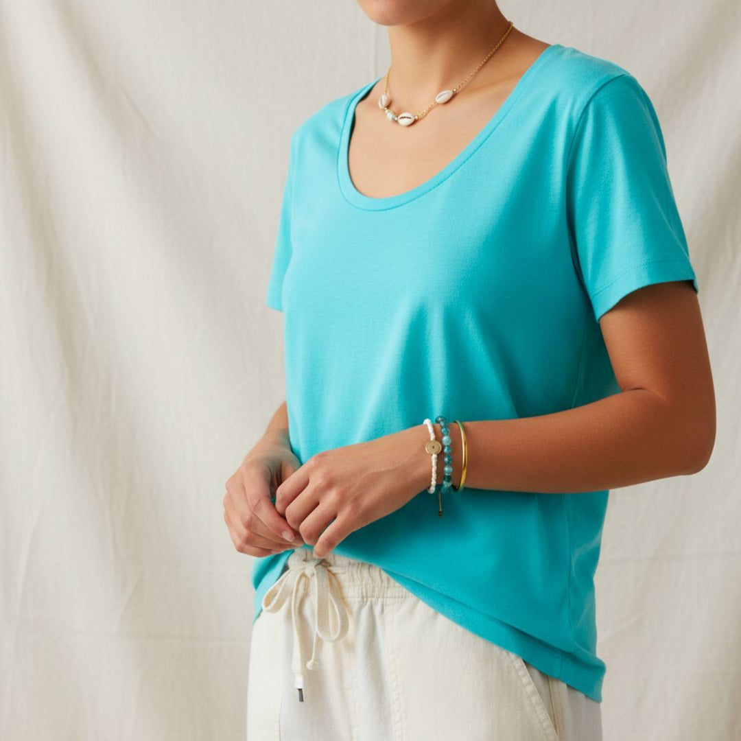 Person wearing a cotton turquoise shirt and white pants against a neutral background