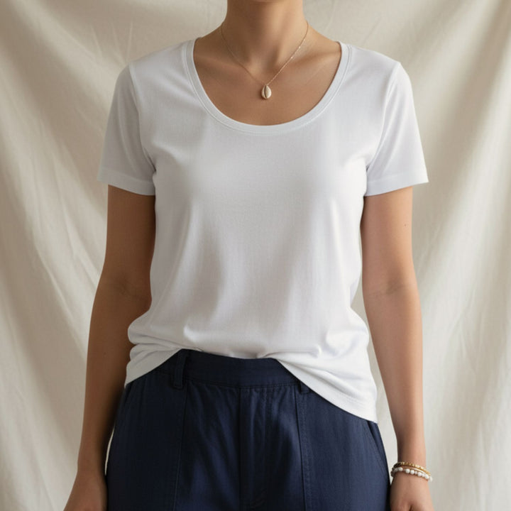 Person wearing a plain white cotton t-shirt and navy pants against a neutral background