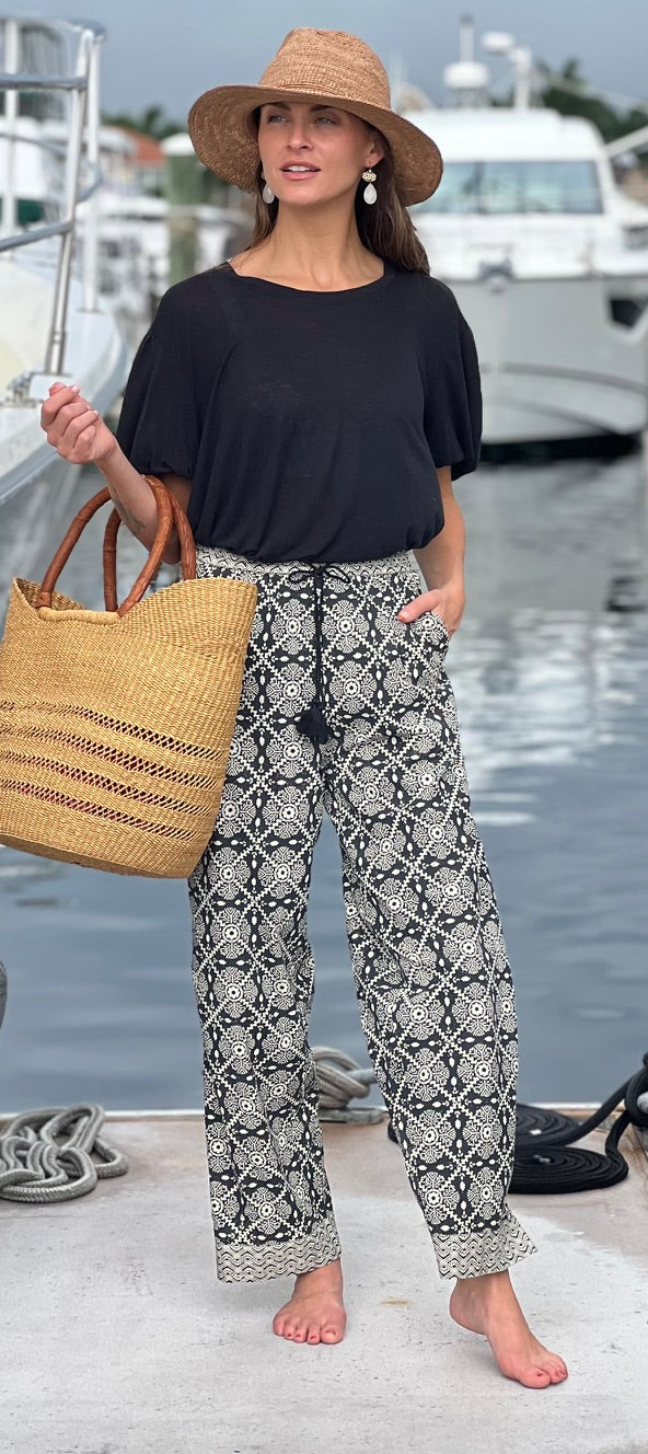 Woman in black top and patterned pants standing by a marina