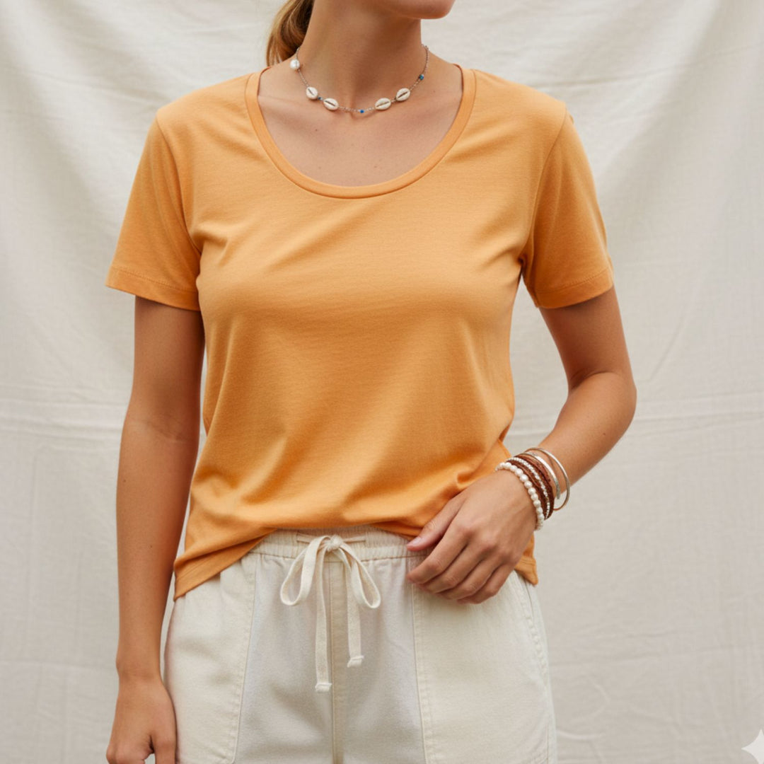 Person wearing a cotton mustard yellow t-shirt and white pants against a neutral background