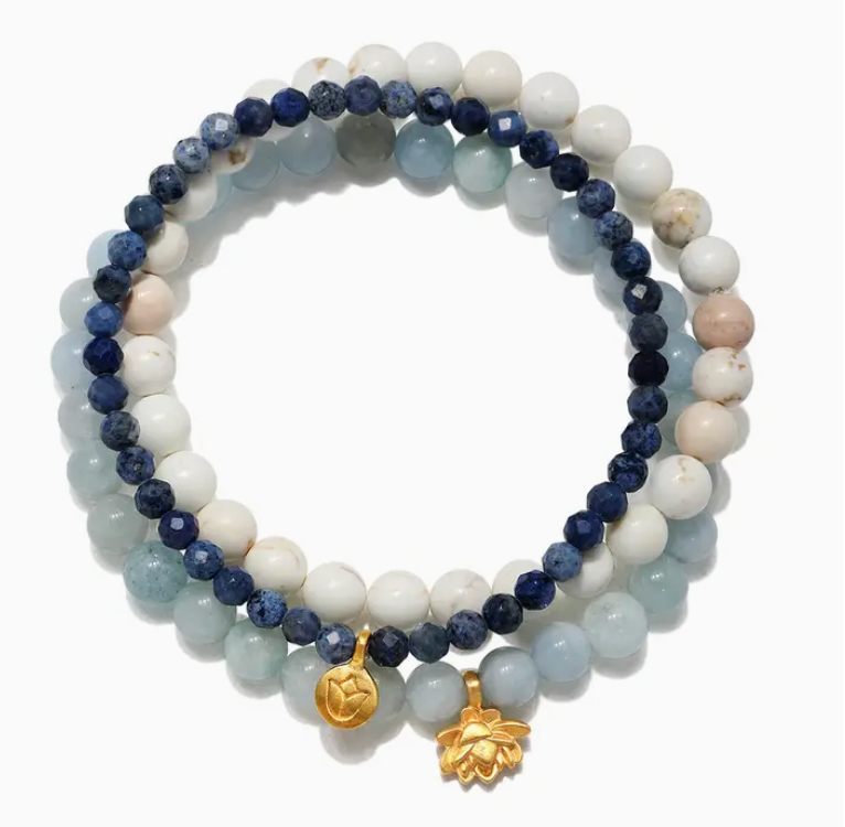 Stack of beaded bracelets with blue, white, and gold accents on a white background