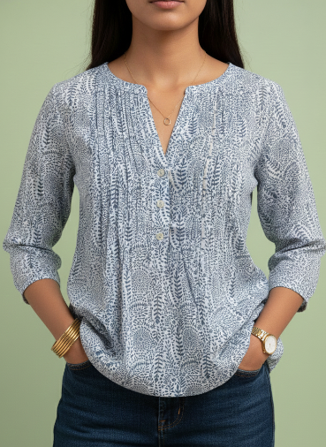 Woman wearing a patterned blouse and jeans against a green background