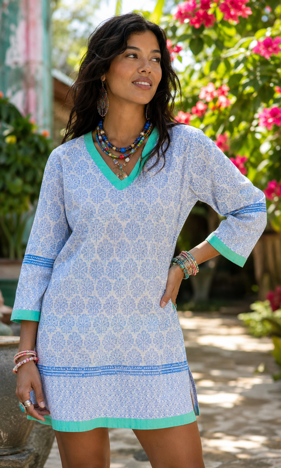 Woman wearing a blue patterned dress with green trim in a garden setting