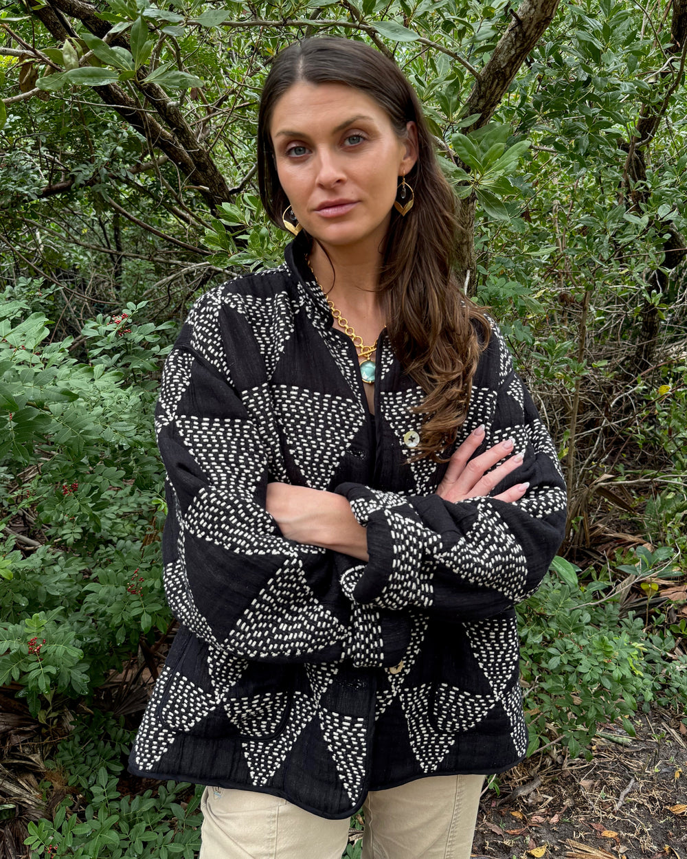 Woman wearing a black and white patterned jacket in a forest setting