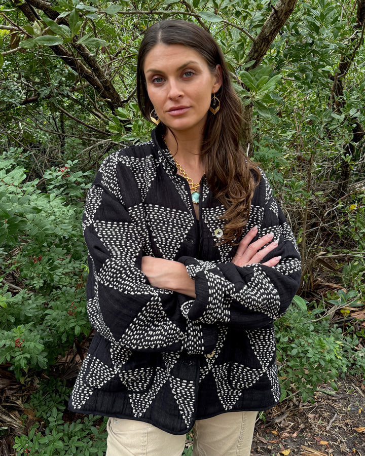 Woman wearing a black and white patterned jacket in a forest setting