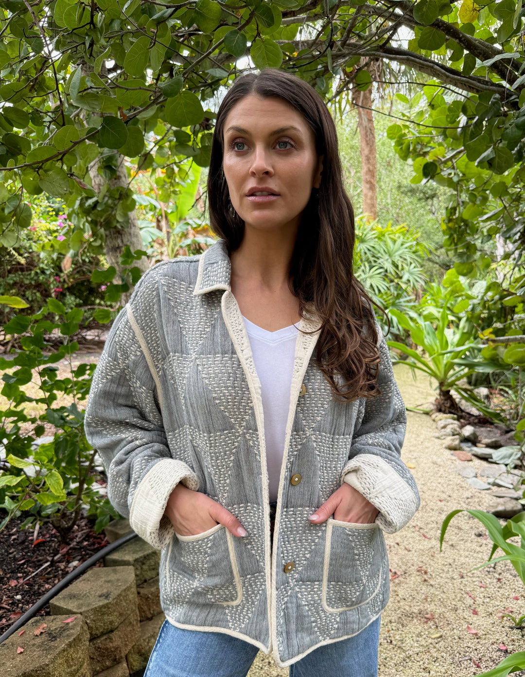Woman wearing a patterned jacket and jeans standing in a garden