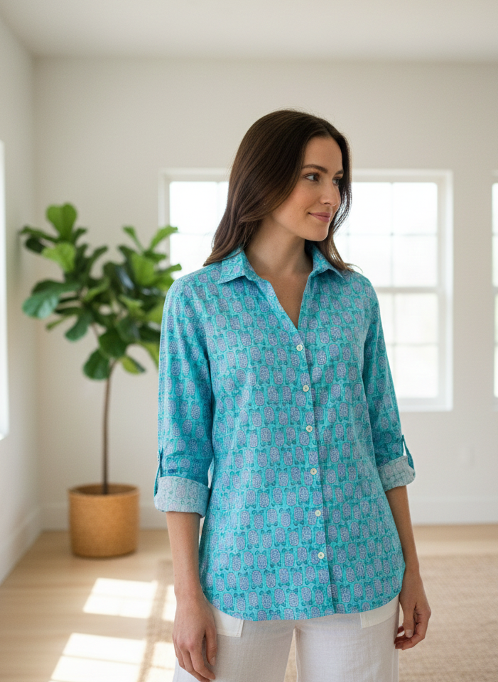 Woman wearing a blue patterned shirt in a bright room with large windows.