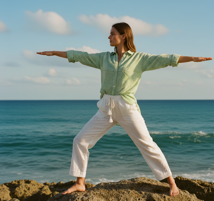 Person practicing yoga on a rocky outcrop by the ocean