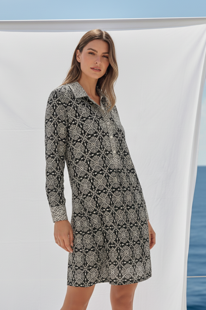 Woman wearing a patterned dress standing against a white curtain with ocean view