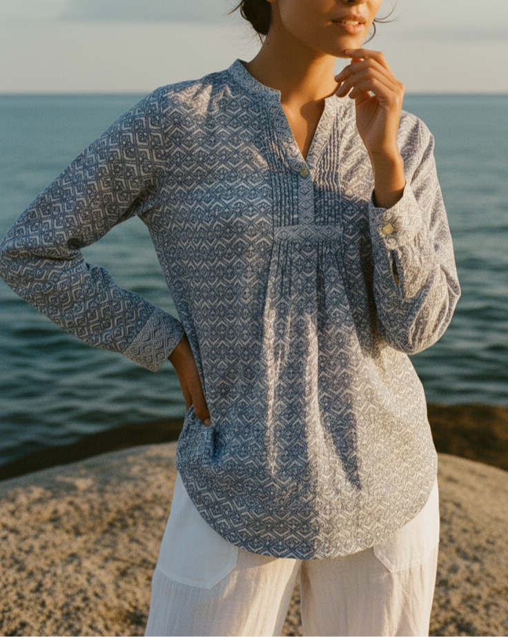 Woman wearing a patterned blue shirt by the ocean