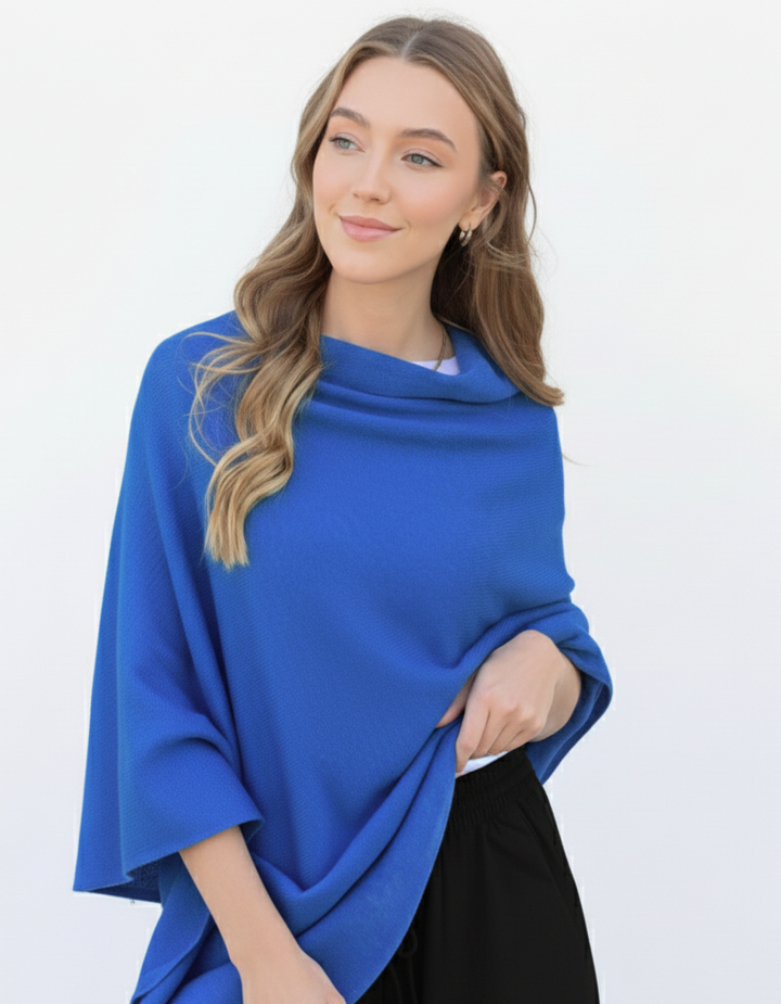 Woman wearing a blue poncho against a white background