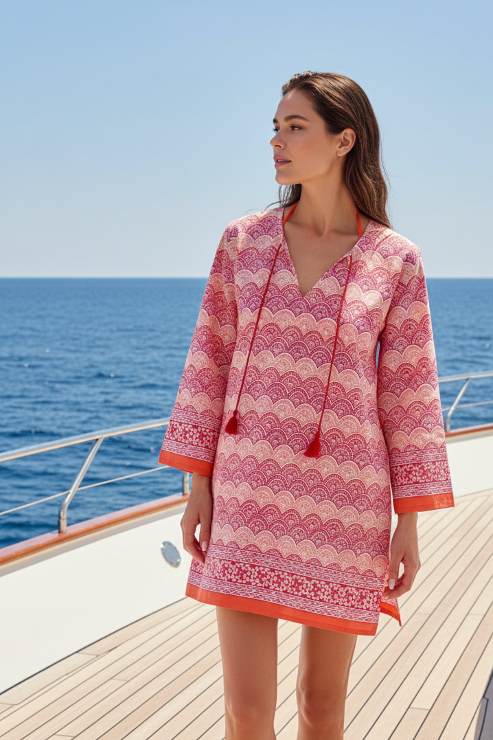 Woman in a pink dress with lace details on a boat deck with ocean view