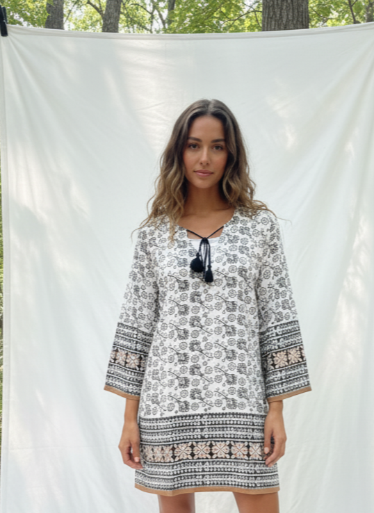 Woman standing in a forest wearing a loose fitting tunic with a white backdrop
