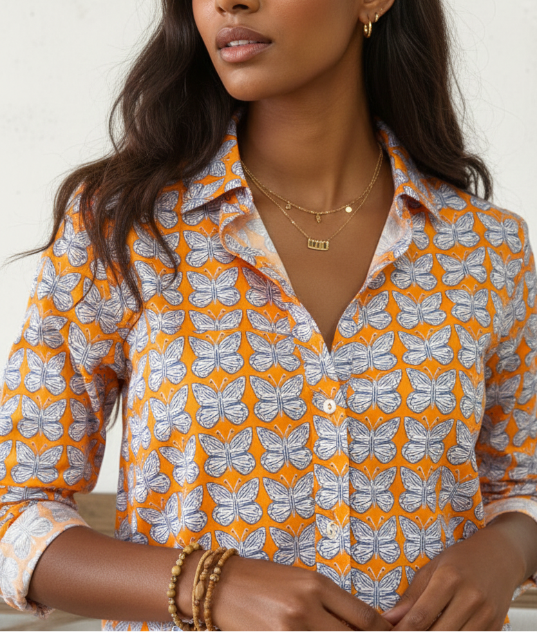 Woman wearing a patterned shirt with orange and white colors on a plain background
