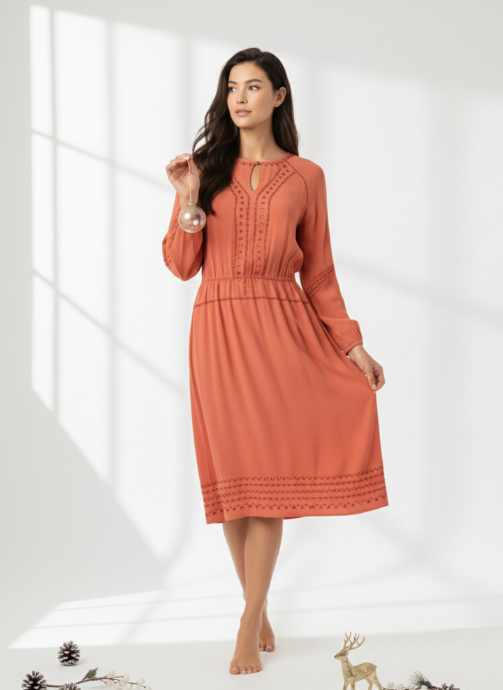Woman wearing an orange dress standing in a bright room with minimal decor.