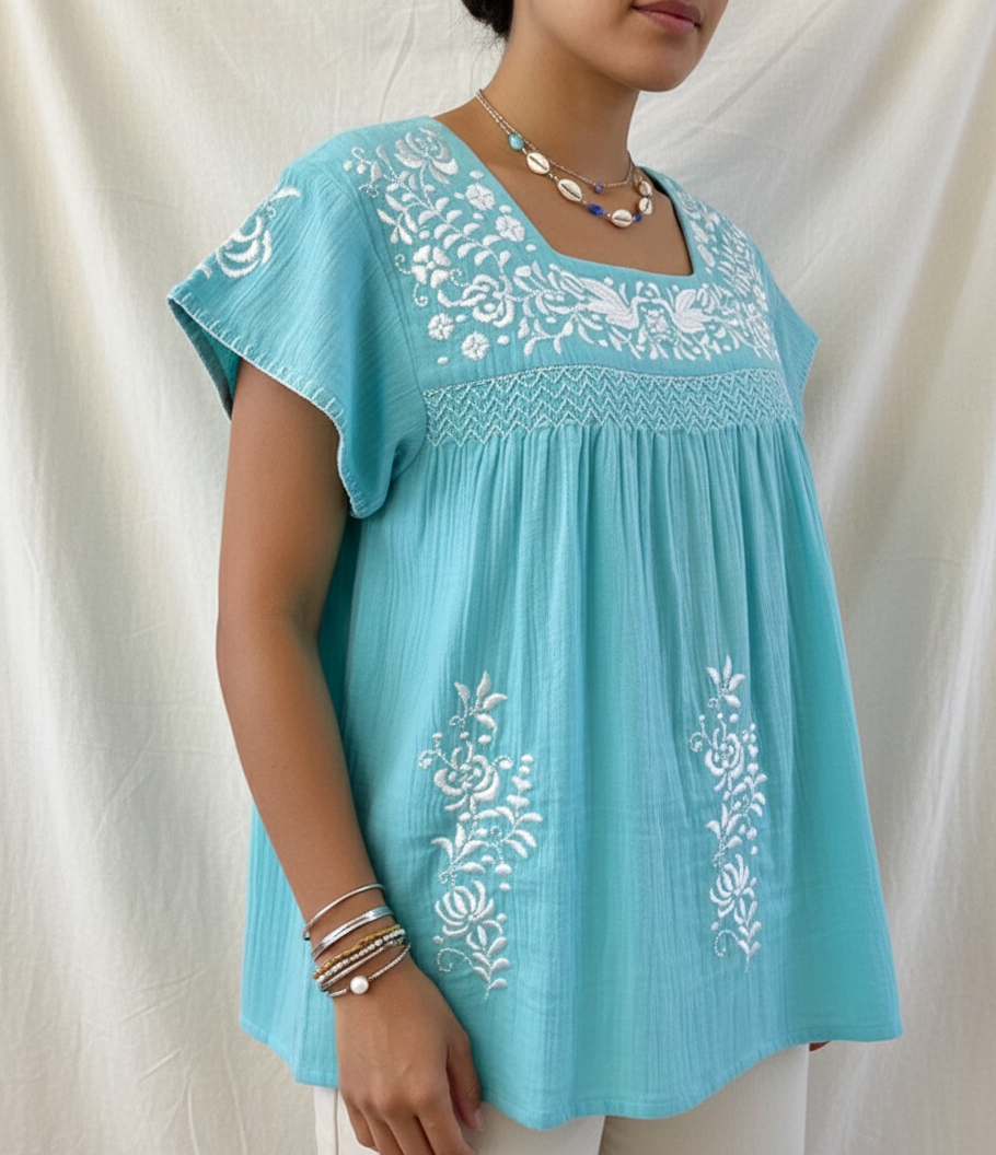Light blue embroidered cotton top worn by a person on a white background