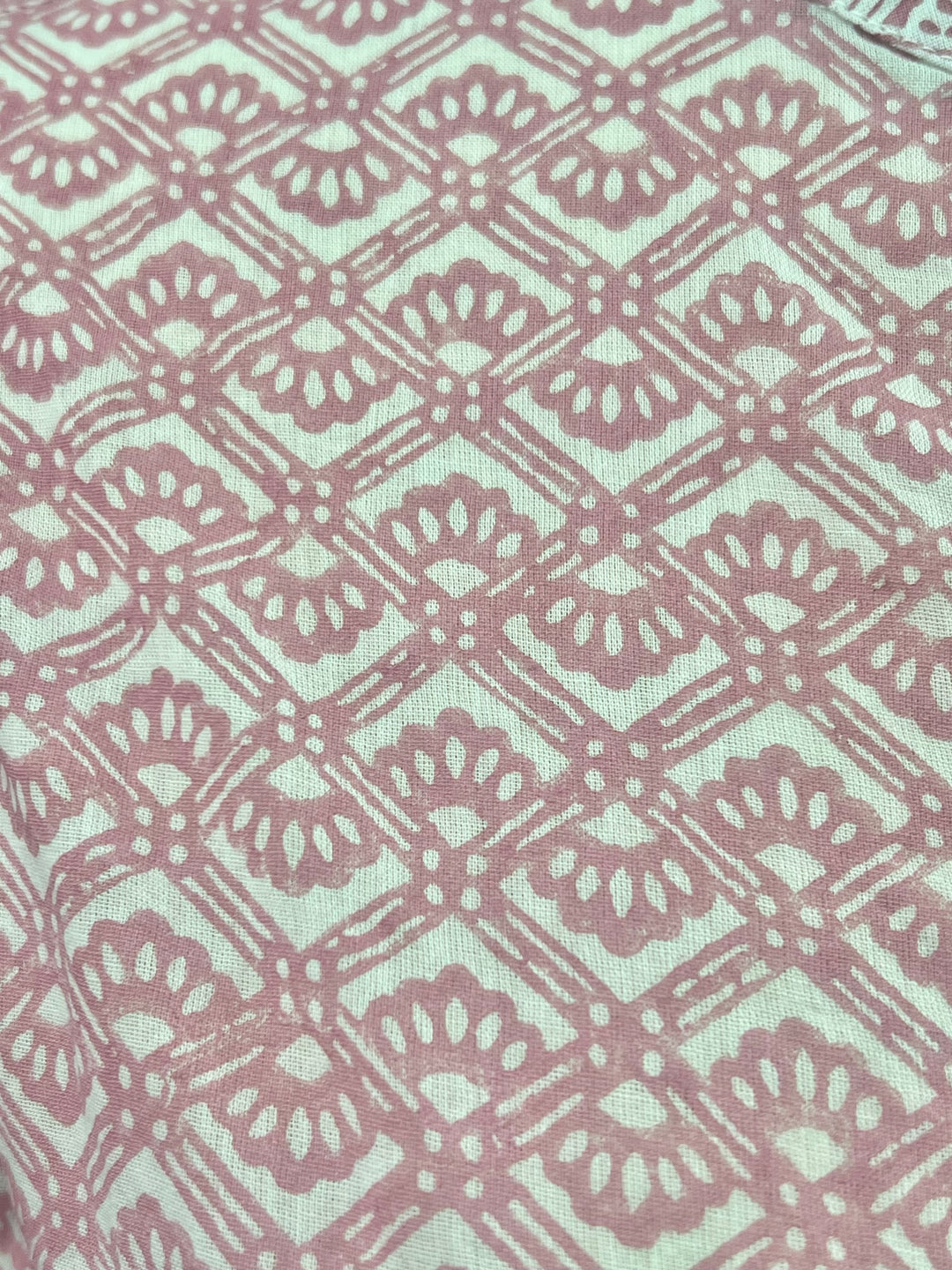 Patterned fabric with a geometric design in pink and white on a light blue background
