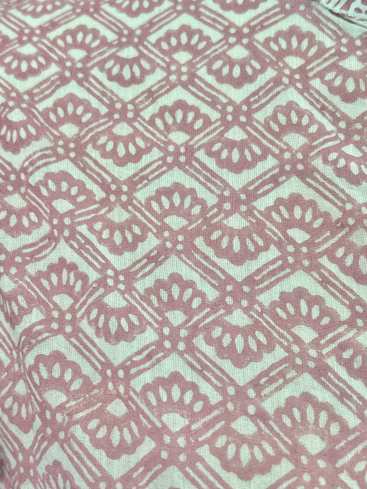 Patterned fabric with a geometric design in pink and white on a light blue background