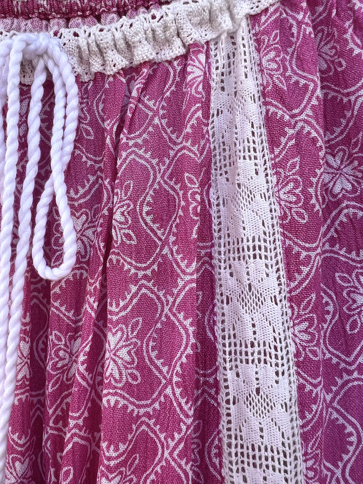Close-up of a pink patterned fabric with white lace trim and drawstrings.