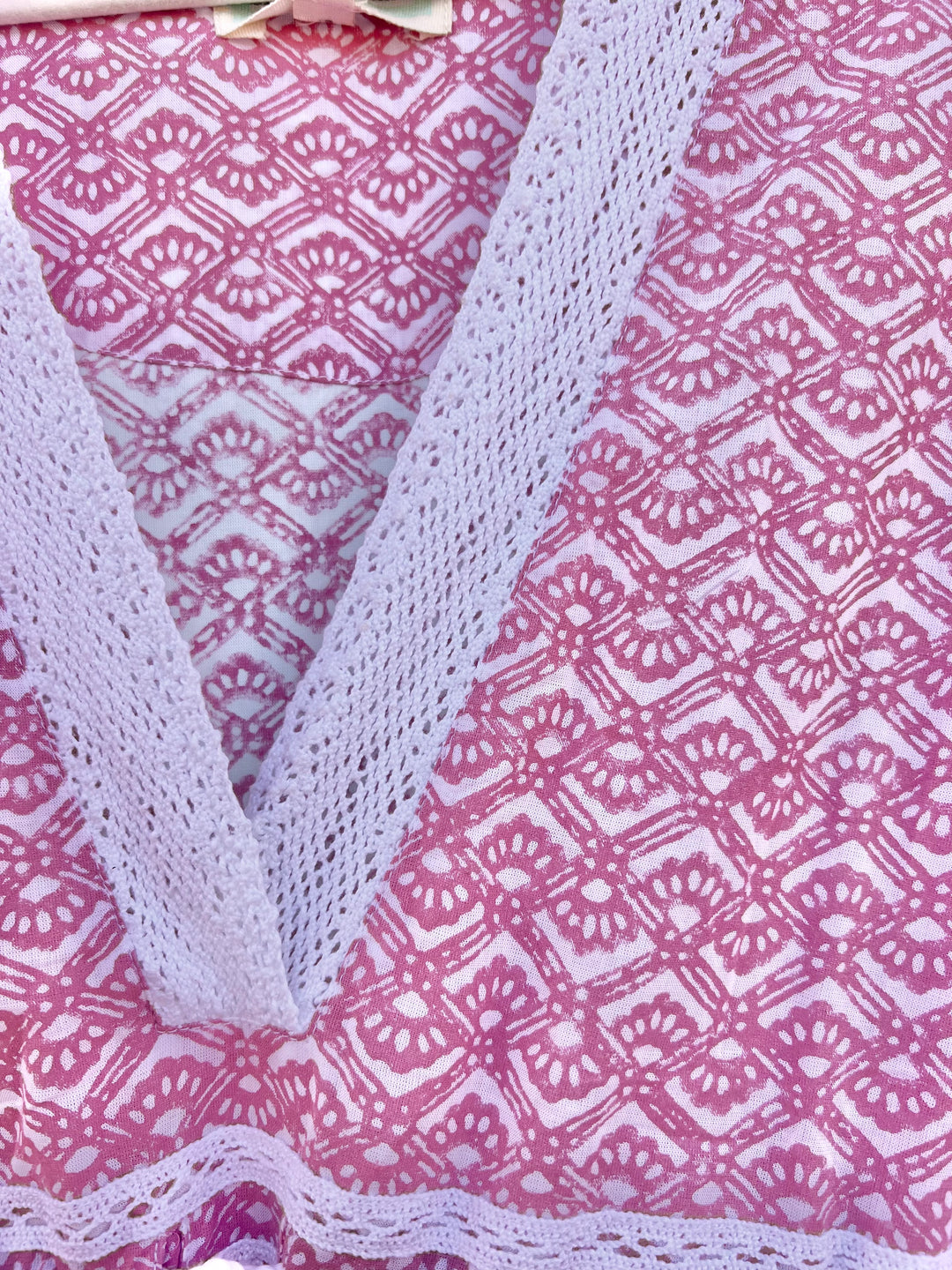 White lace fabric over a pink patterned fabric background