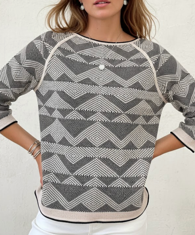 Woman wearing a gray and white patterned sweater with a plain background