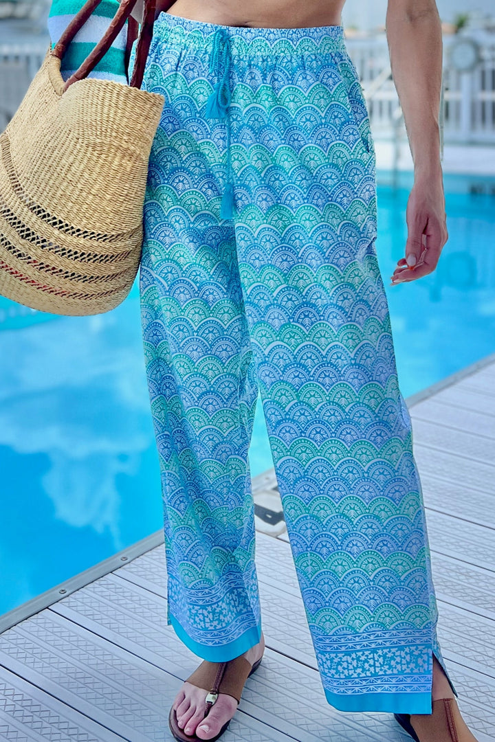woman standing in front of a pool in light blue printed pants