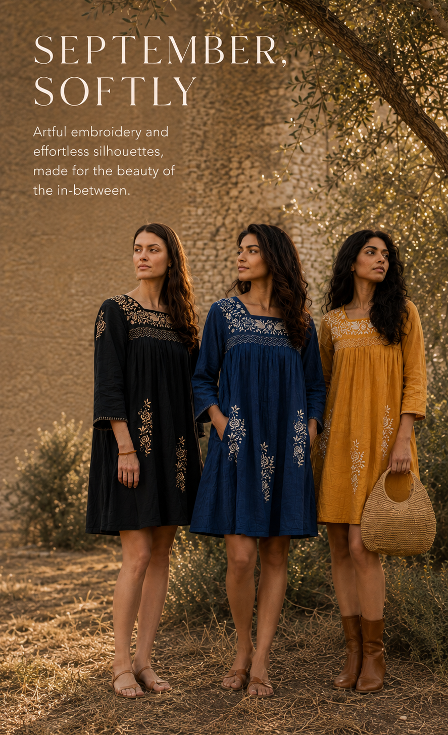 Three women stand outdoors in a sunlit wooded setting wearing embroidered dresses in black, navy blue, and mustard yellow. Large text at the top reads 'SEPTEMBER, SOFTLY' with descriptive copy about embroidered silhouettes.