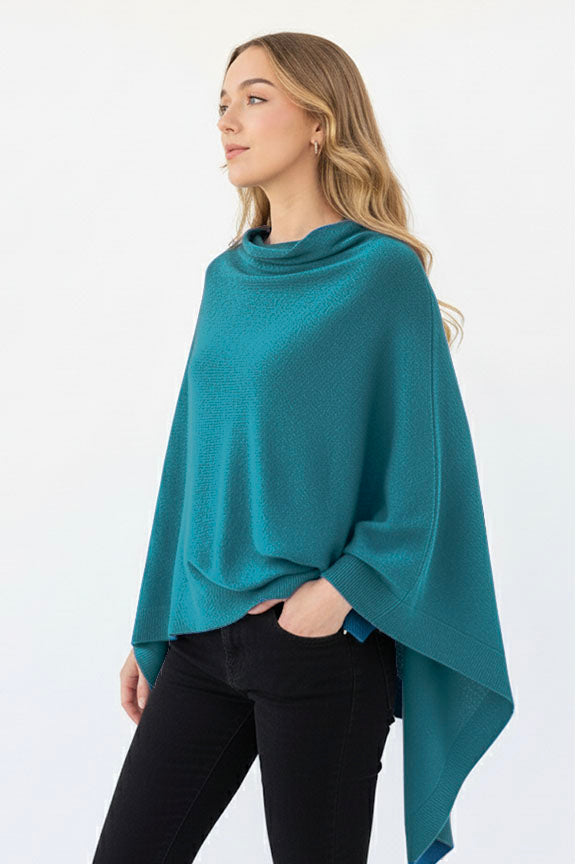 Woman wearing a teal poncho against a white background