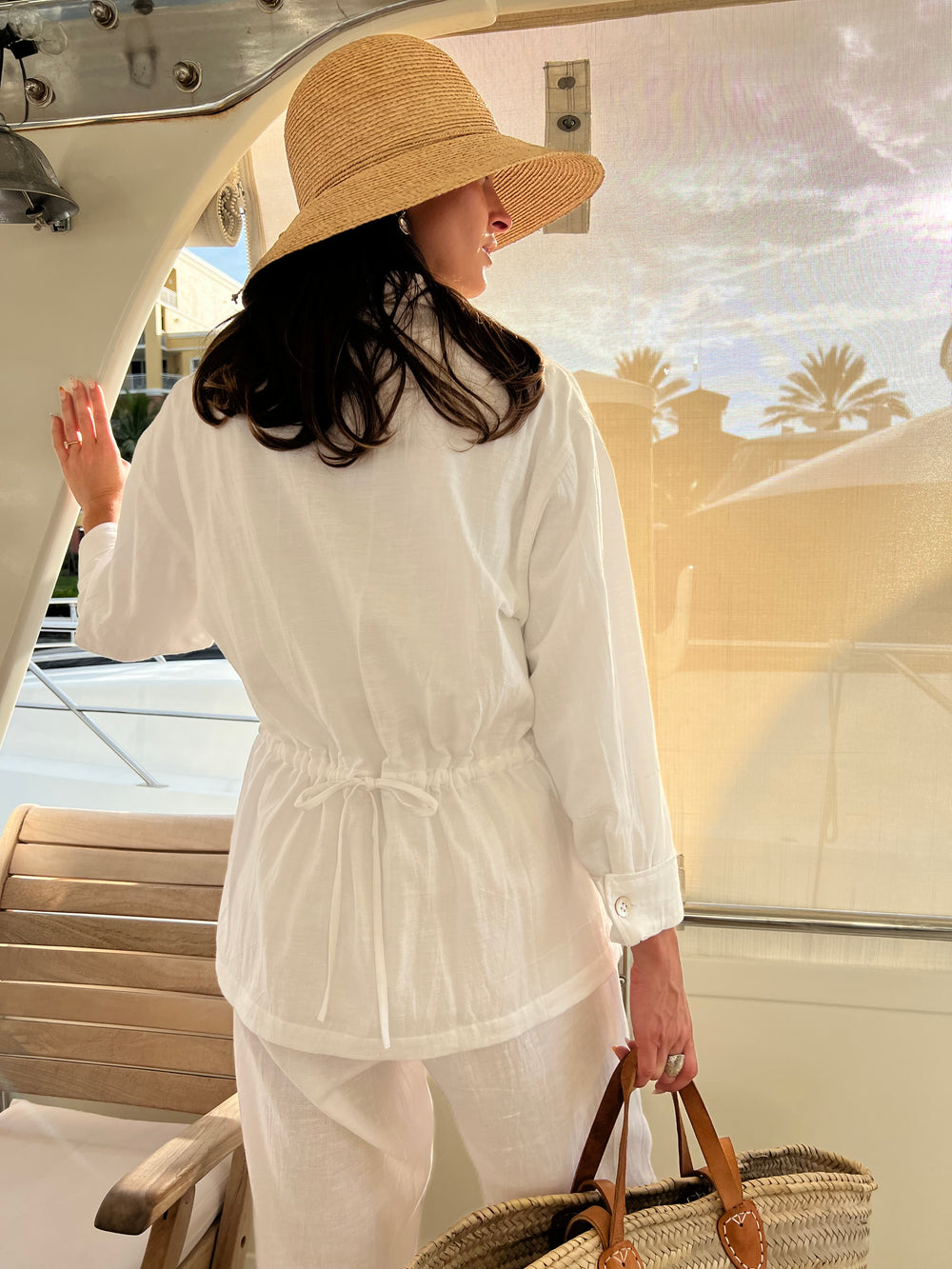 the back of a woman in all white outfit on a boat